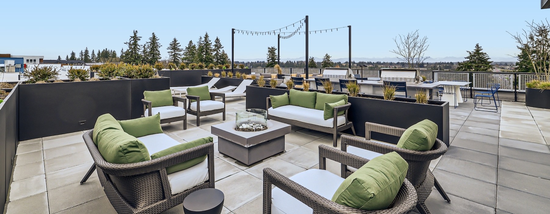 a rooftop patio with chairs and tables and a fire pit