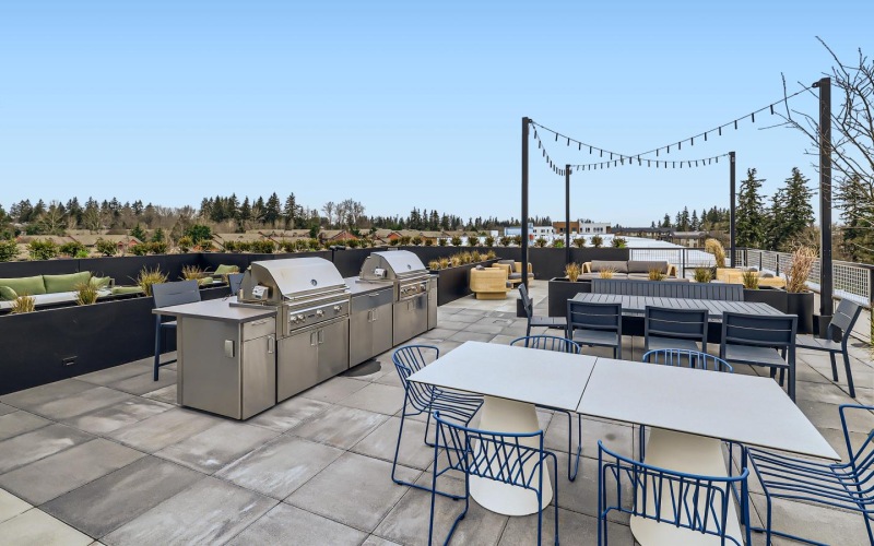 a spacious grilling patio with tables, chairs, and sofas