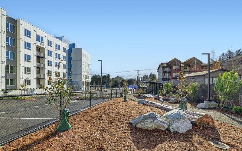 a fenced-in dog park with large rocks and trees