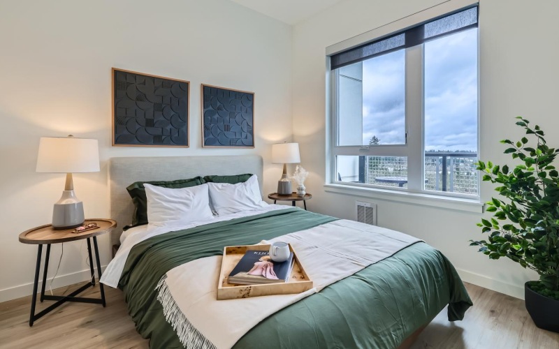 a bedroom with a large window, natural light, and wood-style flooring